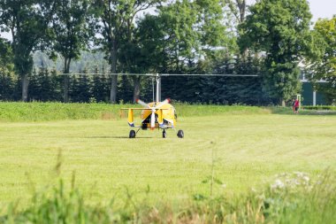 bir çayır üzerinde sarı gyrocopter duran