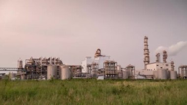 Gün batımında petrol ve kimya endüstrisinde çalışan, tank, yığın, damıtma kolonu ve ofisle birlikte petrokimya fabrikasının zamanaşımına yaklaşılırken