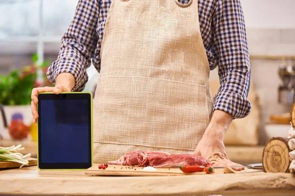 Chef  butcher showing digital tablet in the modern authentic kitchen Recipy application tablet mockup
