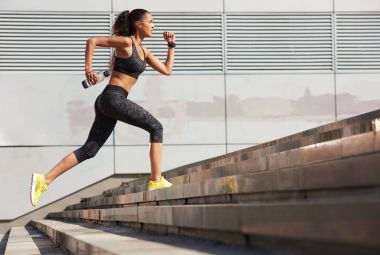 Atletik kadın fitness izci ile şehirde su şişe taş merdivenle çalışan