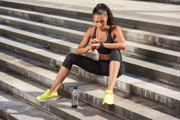 Kvinna idrottsman med Aktivitetskontroll tracker eller puls efter körs på begreppet trappor utomhus fitness. — Stockfoto