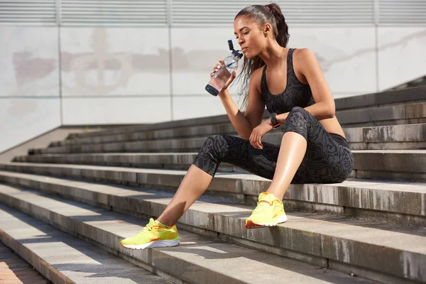 Fitness atleta mulher beber água de garrafa de esporte após o treinamento duro correr — Fotografia de Stock