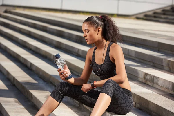 Aptidão atleta sedento mulher lokking no esporte garrafa após o treinamento duro correr — Fotografia de Stock