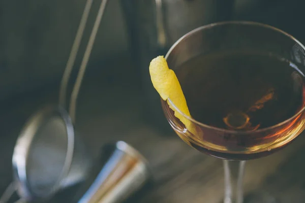 Коктейль из спиртного в стакане купе с лимоном и шейкером — стоковое фото
