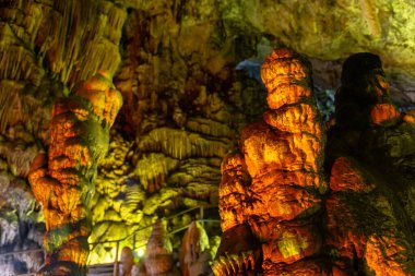 Mağara kaya oluşumları sarkıtlar ve renkli ışık altında dikitler. Karanlık salonda, Zeus Mağarası, Girit 'te dikitlerin oluşumunun mucizesi. Tatil ve seyahat konsepti. at yarışı