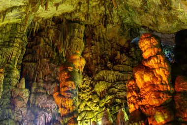 Mağara kaya oluşumları sarkıtlar ve renkli ışık altında dikitler. Karanlık salonda, Zeus Mağarası, Girit 'te dikitlerin oluşumunun mucizesi. Tatil ve seyahat konsepti. at yarışı