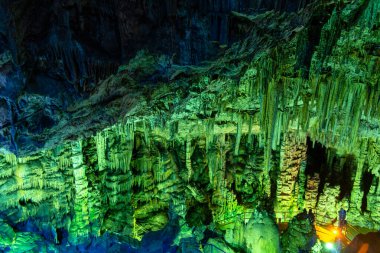 Mağara kaya oluşumları sarkıtlar ve renkli ışık altında dikitler. Karanlık salonda, Zeus Mağarası, Girit 'te dikitlerin oluşumunun mucizesi. Tatil ve seyahat konsepti. at yarışı