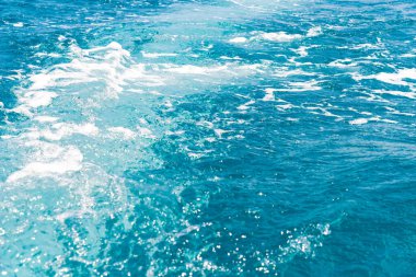 Güneşli yansımalı mavi okyanus suyu. Dalgalı berrak mavi su çok yakın. Rahat seyahat konsepti. Arka plan yatay çerçevedir. Metin için boşluk.