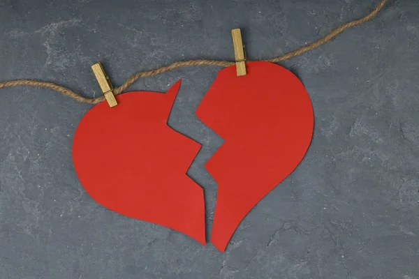 red broken heart on rope . concrete background