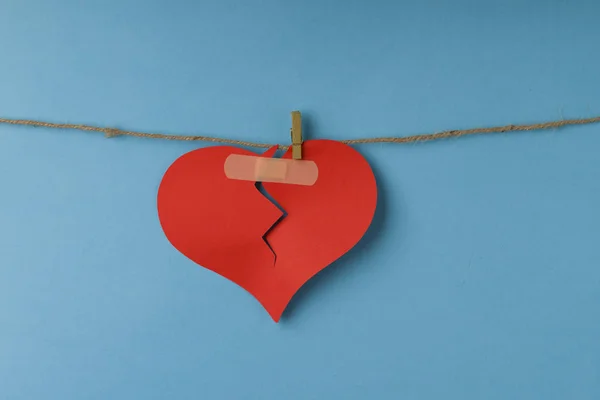 Broken paper heart hanging on rope