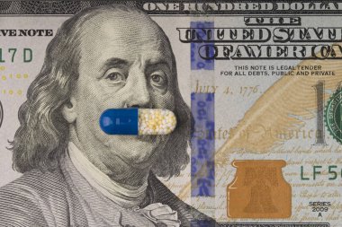 Drugs pill on the Ben Franklin's mouth of hundred-dollar bill. h