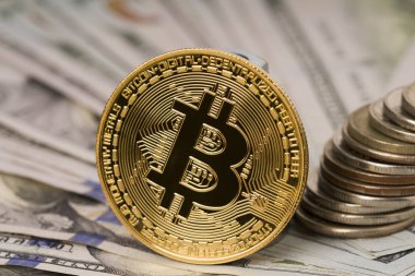 Dolar banknotlarının önünde duran altın bitcoin. Bitcoin 'in fiziksel versiyonu bitcoin ile bir dolar konseptini değiş tokuş