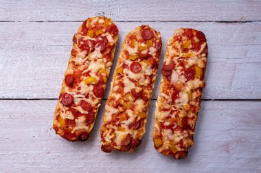 Salamlı ve beyaz ahşap arka planlı pizza ekmeği.