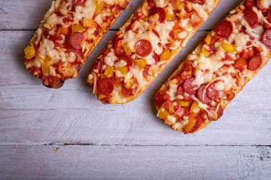Salamlı ve beyaz ahşap arka planlı pizza ekmeği.