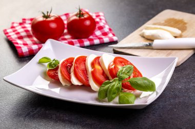 beyaz bir tabak yakın çekim üzerinde fesleğen ile mozzarella ve domates caprese salatası