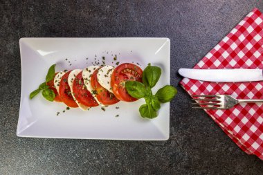 beyaz bir tabak yakın çekim üzerinde fesleğen ile mozzarella ve domates caprese salatası