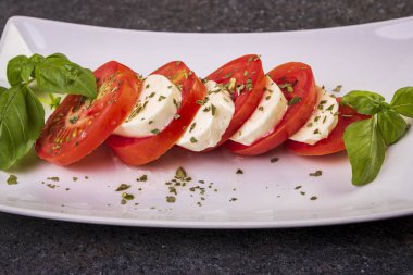 beyaz bir tabak yakın çekim üzerinde fesleğen ile mozzarella ve domates caprese salatası