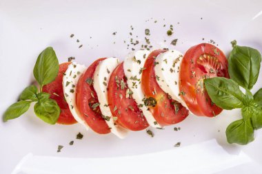 beyaz bir tabak yakın çekim üzerinde fesleğen ile mozzarella ve domates caprese salatası