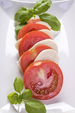 beyaz bir tabak yakın çekim üzerinde fesleğen ile mozzarella ve domates caprese salatası