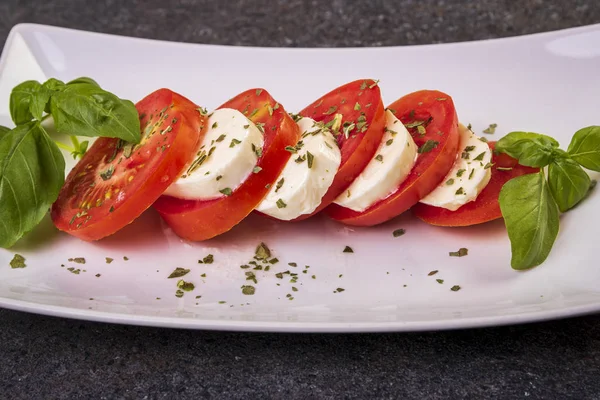 beyaz bir tabak yakın çekim üzerinde fesleğen ile mozzarella ve domates caprese salatası
