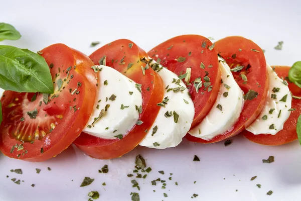 beyaz bir tabak yakın çekim üzerinde fesleğen ile mozzarella ve domates caprese salatası