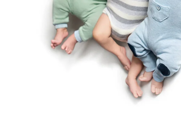 Tre paia di gambe di neonati triplette. Fratelli gemelli. Isolato. Copia spazio — Foto Stock