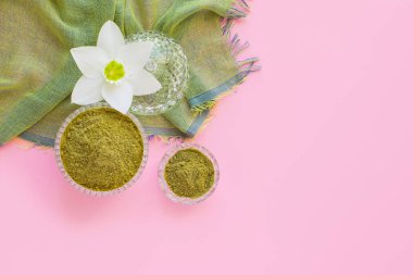 natural henna powder and white flower in a female hand on a pink background. Concept female beauty and cosmetology. Eyebrow and hair coloring.