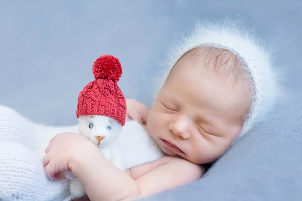 stock image Christmas theme, sleeping newborn baby holding teddy bear in Santa hat, new year eve concept, lights