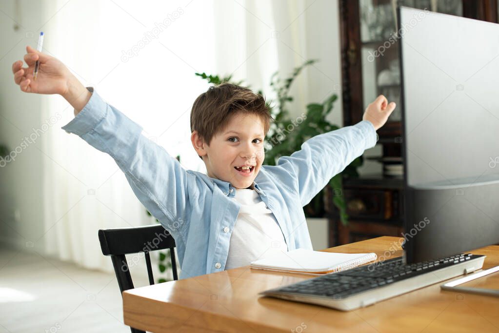 Distance learning in quarantine in coronavirus. Lifestyle. Portrait of successful boy winner with raised hands. Beautiful shouting, isolated. Happy cute child celebrating success with joy