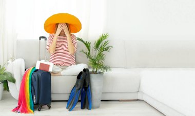 Sarı şapkalı güzel kız evde kalıp tatile çıkmayı planlıyor. Dalış için bavul ve palet. Karantina ve COVID-19 nedeniyle sınırların kapatılması ve uçuşların yasaklanması