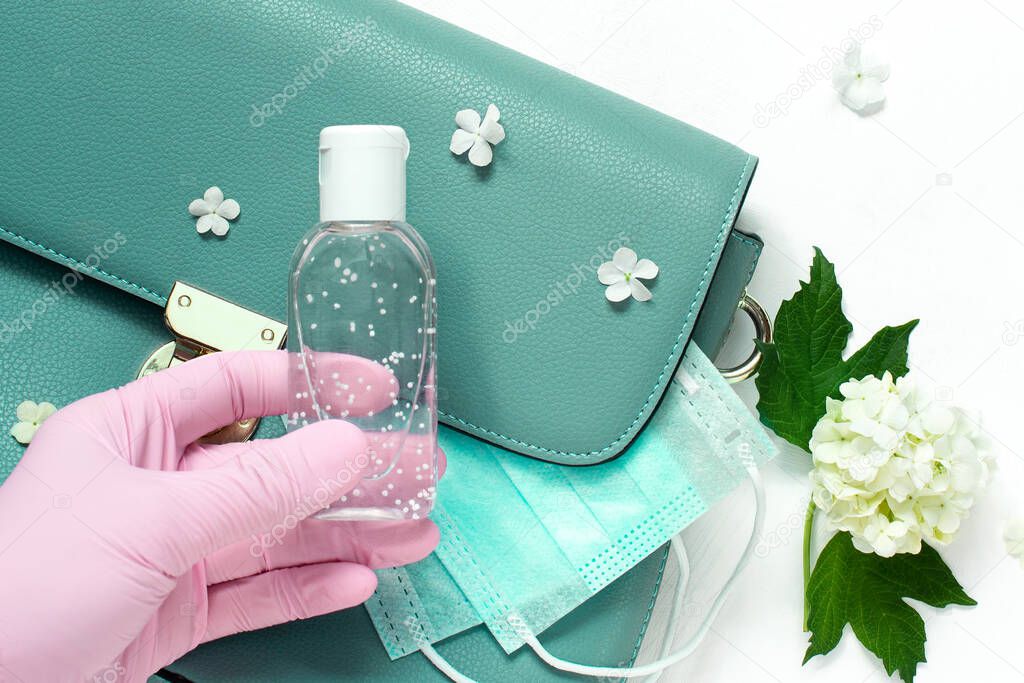 blue leather women bag with a medical mask, a sanitizer and gloves. Concept spring-summer 2020 exit from the coronavirus pandemic. protective equipment after isolation