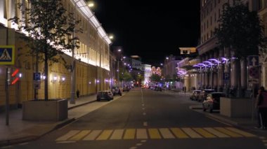 Gece şehir caddesinin odağından çıkmış görüntüsü. Arabalar yol boyunca gider. İnsanlar yürür
