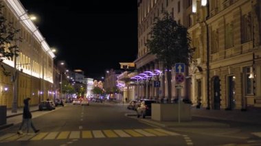 Gece şehir caddesinin odağından çıkmış görüntüsü. Arabalar yol boyunca gider. İnsanlar yürür
