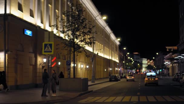 Rozkojarzony widok na ulicę nocną. Samochody jadą wzdłuż drogi. Ludzie chodzą. — Wideo stockowe