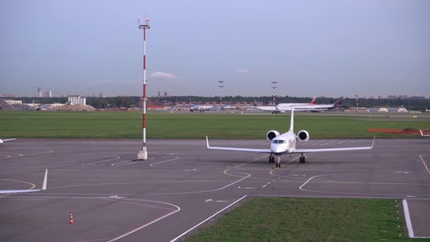 Op de parkeerplaats van het vliegveld staat het vliegtuig geparkeerd. Landingsvliegtuig op de achtergrond — Stockvideo