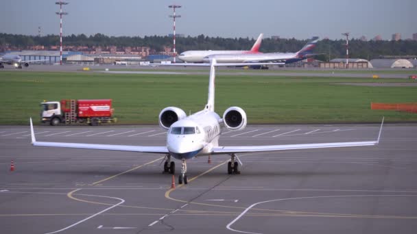 飛行機は空港に駐機されています給油機用燃料付きトラックが通過します — ストック動画