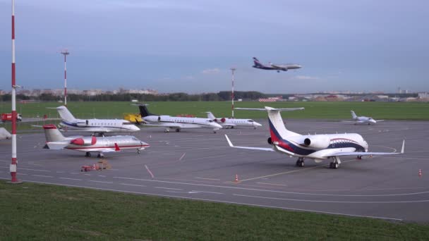 Op de parkeerplaats van het vliegveld staan vliegtuigen geparkeerd. Vliegtuig landt op de landingsbaan. 4k — Stockvideo