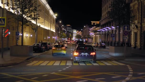 Vista de una concurrida calle de la ciudad. Buenas noches. Tráfico pesado. Coloridas fachadas de edificios. 4K — Vídeos de Stock