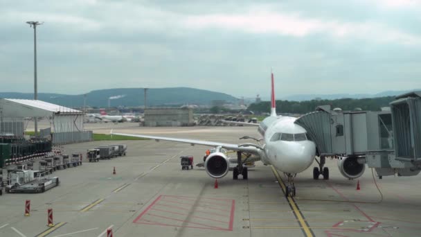 O avião está estacionado perto do terminal. Túnel de embarque ligado ao avião. 4K — Vídeo de Stock