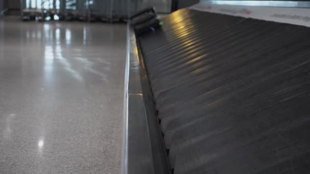 Twee koffers bruin en zwart, naderen op een transportband op het vliegveld — Stockvideo