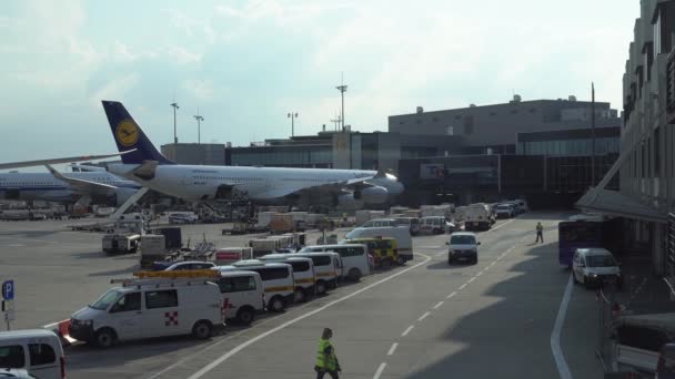 Samolot linii lotniczych Lufthansa jest zaparkowany w pobliżu tunelu transportowego. Samochody na lotnisko — Wideo stockowe