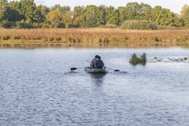 Teknedeki avcılar yaban ördeklerini aramak için gölette yüzerler.