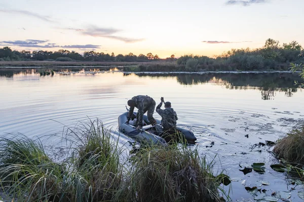 Jägare i en båt simmar i en damm på jakt efter vilda ankor — Stockfoto