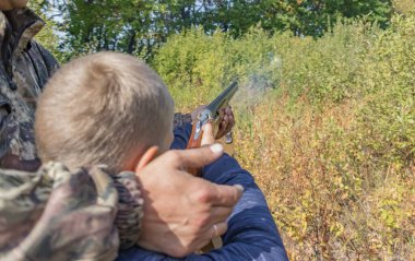 Baba oğluna av tüfeği kullanmayı öğretiyor.