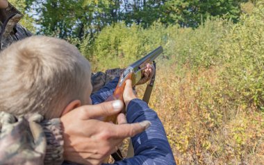 Baba oğluna av tüfeği kullanmayı öğretiyor.