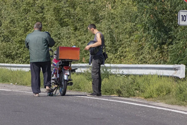 Motorcyclist inflates a broken wheel by the highway