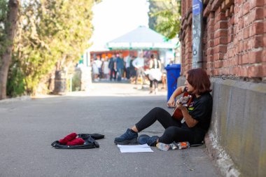 Bahşiş için sokakta gitar çalan genç bir kız.