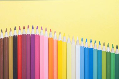 Sıraya dizilmiş çok renkli güzel kalemler, bulanık arkaplan.