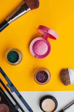 Parlak oje ve dekoratif kozmetik ürünleri sarı, turuncu ve kremalı arka planda. Asgari düzeyde. Uzayı kopyala Güzellik blogcusu kavramı. Üst görünüm.