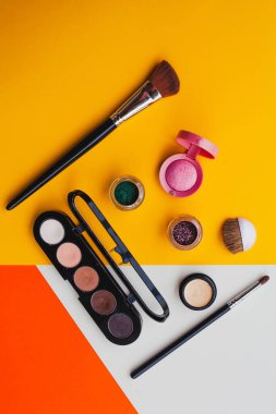Parlak oje ve dekoratif kozmetik ürünleri sarı, turuncu ve kremalı arka planda. Asgari düzeyde. Uzayı kopyala Güzellik blogcusu kavramı. Üst görünüm.
